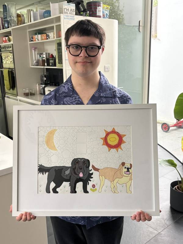 Nicky holding a framed drawing of two dogs